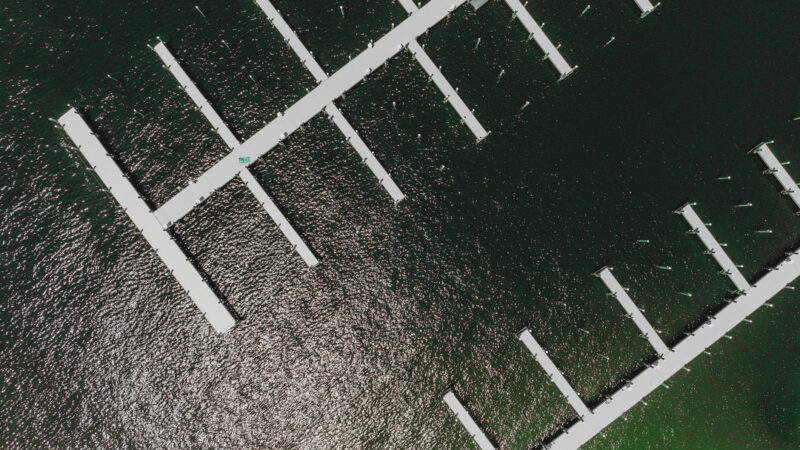 Aerial view of a marina deep water docks surrounded by sparkling green water, located in Fort Walton Beach.